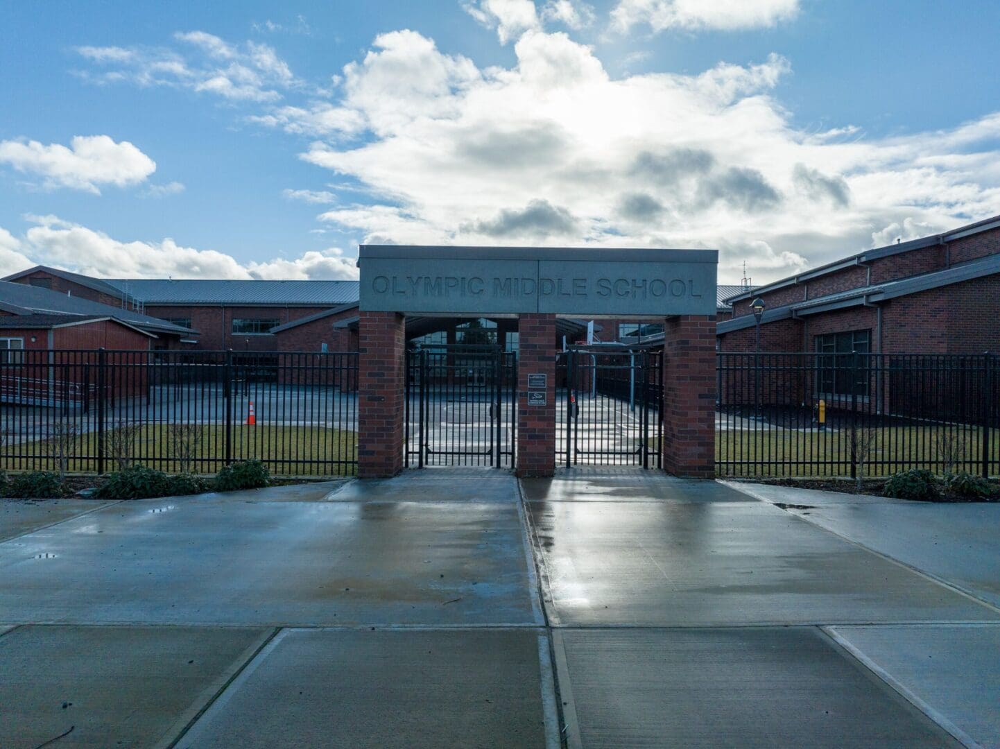 The entrance to a school with a fence and a cloudy sky.