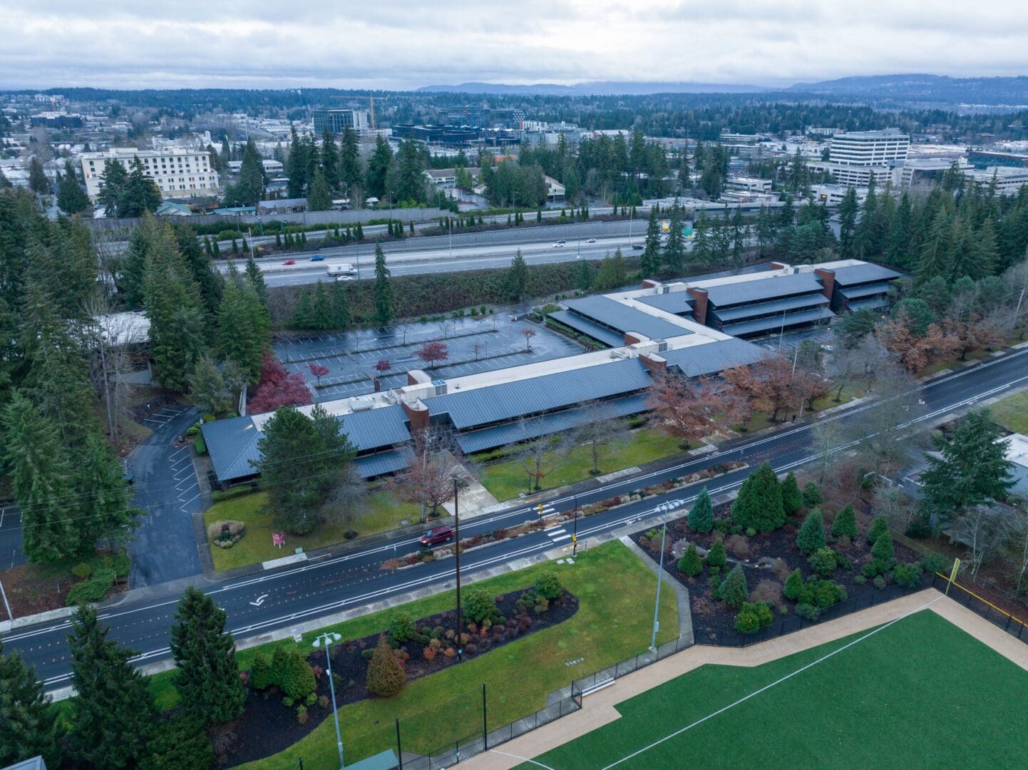An aerial view of a campus with a soccer field and trees.